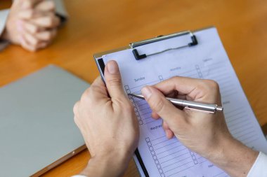 Close up clipboard in a hand manager write take note candidate interview with corporate business. Satisfaction survey of service providers and employees.