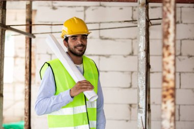 Adam mühendis, bina inşaatında şablon çizimi tutuyor. Erkek mimar ev inşaatında duruyor. Ustabaşı iş yerinde.