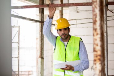 Adam mühendis, bina inşaatında şablon çizimi tutuyor. Erkek mimar ev inşaatında duruyor. Ustabaşı iş yerinde.