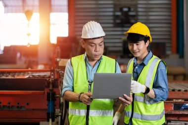 İmalat fabrikasında çalışan bir mühendis takımı dizüstü bilgisayar kullanıyor. Ekip çalışması teknisyeni metaller otomatik mekanik enerji projesi.
