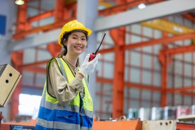 Kadın mühendis elinde telsiz kalite kontrolüyle fabrika deposunun önünde duruyor. profesyonel mühendislik makine atölyesi.