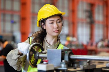 Kadın mühendis, fabrikada çalışırken şapka takıyor. Kadın teknisyen metal torna endüstrisini kontrol ediyor. Kadın atölye teknolojisi üretimi.