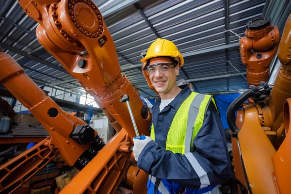 portrait of man engineer standing at automation robot arms machine in factory. repairman of welding robots in production. technology intelligence electronic innovation.