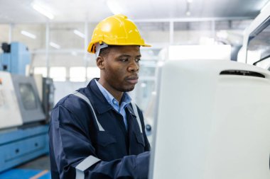 Man African American engineer using computer controlling cnc machine at workshop. professional male control automated machine process programming cnc machine at industry manufacturing.