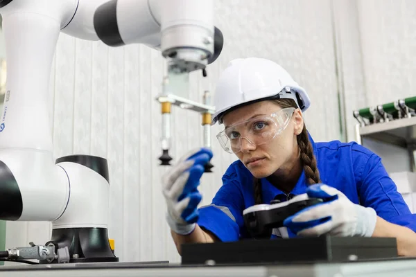 female technician engineer using remote control and checking automation robotics at industrial modern factory. woman working at factory innovation automation robot.