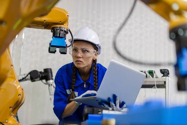 female technician engineer using laptop checking automation robotics at industrial modern factory. woman working at factory innovation automation robot.