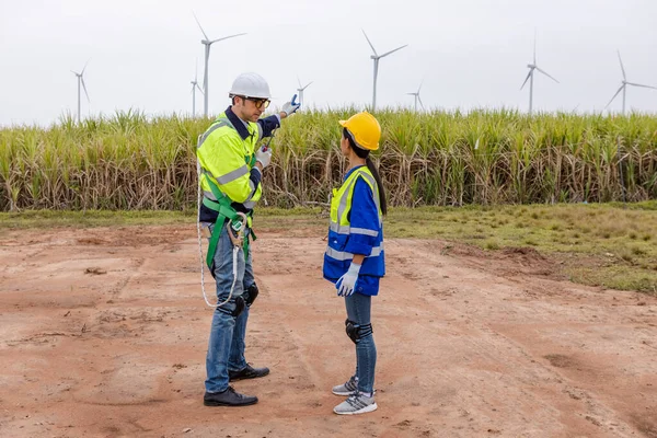 Team engineer of wind turbine worker pointing working about renewable energy at station energy power wind. technology protect environment reduce global warming problems.