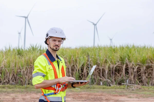 Man engineer of wind turbine worker using laptop working about renewable energy at wind farm. energy power wind. technology protect environment reduce global warming problems.
