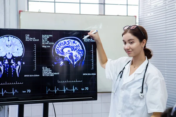 Doctor woman presentation of brain x-ray results through screen to present to medical team in meeting room. Showcases treatment of nervous system and brain.