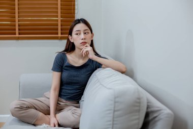 Evdeki kanepede oturan kadının endişeleri var..