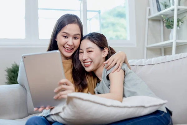 快乐的女性情侣们坐在家里的沙发上 用数字平板电脑在网上购物 漂亮女人女朋友的生活方式 — 图库照片