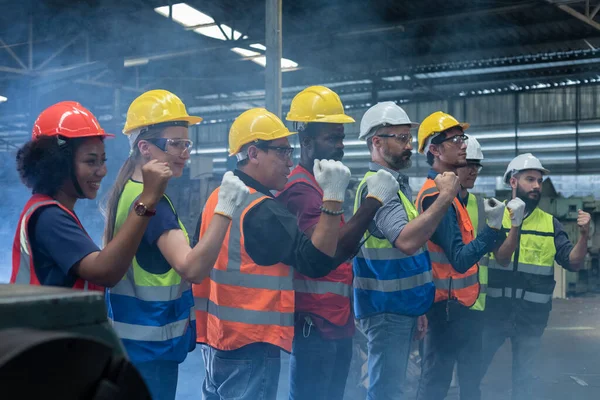 Group of various nationalities engineer professional successful team corporate workers standing in factory with smoke. teamwork technician inspector manufacturing industry workplace.