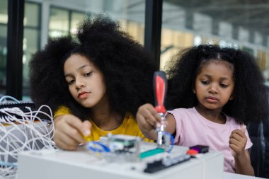 Sınıftaki masada afro saç stili eğitimli elektronik çocuk. Gelecekteki yapay zekalar için elektronik öğrenme teknolojisi. Elektrik sistemi eğitimi. BTMM eğitim kavramı.