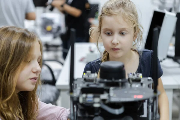 Kafkas eğitimi alan bir kız, sınıf odasındaki masada elektronik robot. Gelecekteki yapay zekalar için robot elektroniği öğreniyorum. Sistem becerisi eğitimi. BTMM eğitim kavramı.