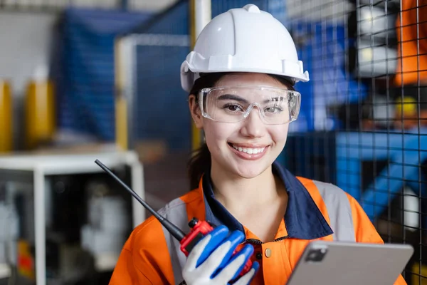 Close up portrait female industrial robotics engineer holding walkie talkie and tablet looking at camera. woman technician modern factory 4.0, Technical supervisor of the robot operation department.