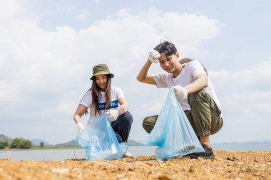 Erkek ve kadın gönüllüler çöp topluyor, çevresel işbirliği yapıyor, dünyayı kurtarıyor küresel ısınmayı azaltıyor, gönüllüler doğal çekimde plastik poşetleri temizliyor..