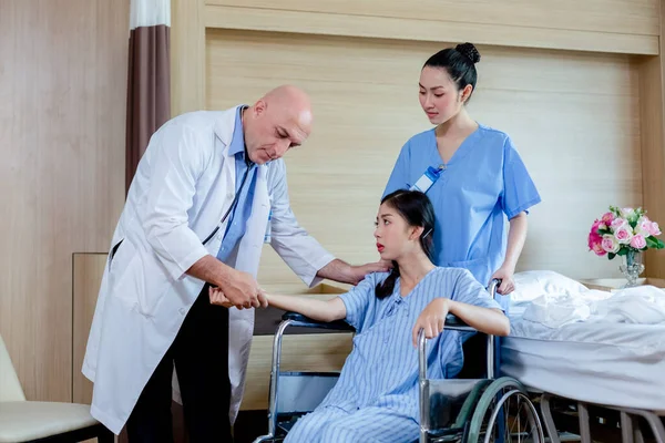 Male doctor and nurse talks to female patient checking pulse in hospital. Doctor man touching hand check pulse for treatment cardiologist. examining heart illness.
