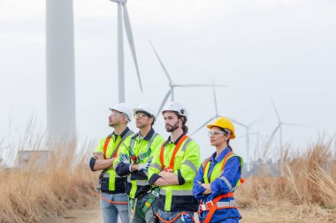 Teamwork engineer wearing safety uniform standing crossed arms at wind turbine field renewable energy. technology protect environment reduce global warming problems. alternative energy concept.