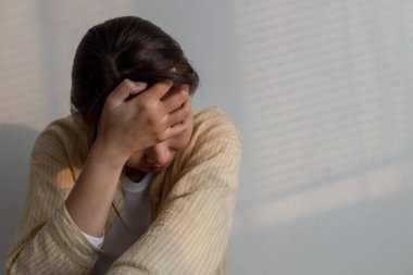 Depresyonda olan bir kadın yalnız başına oturuyor ve yatak odasının köşesini kapatıyor. Kadın baş ağrısı, mutsuz duygu. Depresyonda olan genç zihinsel sağlık sorunları.
