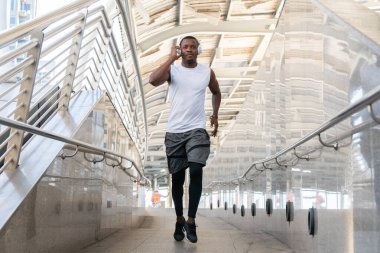 Spor giyim giymiş Afro-Amerikan bir adam sabah vakti dışarıda koşuyor. Genç erkek koşucu spor koşusu, güçlü atletik insan. sağlık hizmeti kavramı.
