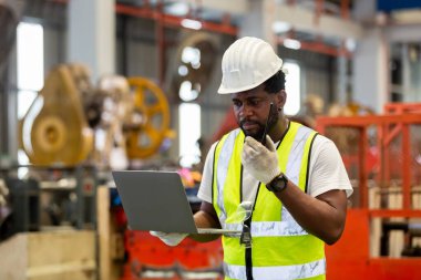 Afrika kökenli Amerikalı mühendis, elinde telsiz olan, bilgisayar kullanarak imalat fabrikasında çalışıyor. teknisyen metal işleri otomatik mekanik enerji projesi.