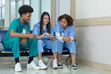 Bir grup tıp öğrencisi ön sınıfta oturmuş tablet kullanarak bilgi araştırması yapıyor ve hastane üniversitesinde konuşuyorlar. eğitim ve öğrenme tıbbi konsepti.