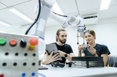 Erkek ve kadın, sınıf odasında eğitim için robotla birlikte tablet mühendisi kullanıyor. Gelecekteki robotik öğrenme yeniliği eğitimi. Atölye bakım teknikleri.