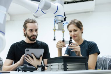 Erkek ve kadın, sınıf odasında eğitim için robotla birlikte tablet mühendisi kullanıyor. Gelecekteki robotik öğrenme yeniliği eğitimi. Atölye bakım teknikleri.