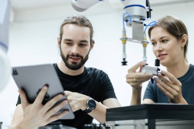 Erkek ve kadın, sınıf odasında eğitim için robotla birlikte tablet mühendisi kullanıyor. Gelecekteki robotik öğrenme yeniliği eğitimi. Atölye bakım teknikleri.