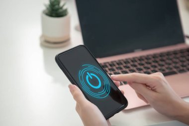 Elektriği kesilen ya da kapatılan akıllı telefon. Kadın el parmağı cep telefonunun ekranına dokunuyor ve düğmeye basıyor. dur için cep telefonu uygulama sembolü.