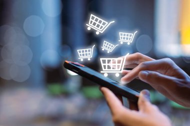 İnternetten akıllı telefon alışverişi yapan bir kadın, ekrandaki cep telefonunda alışveriş arabası simgesi. ödemeyi internetten al. çevrimiçi süpermarket aracı.