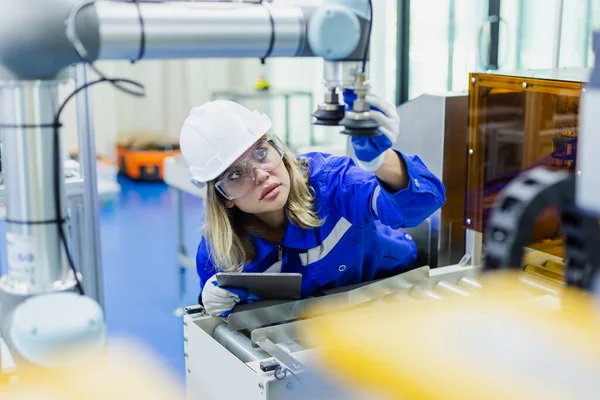 female technician engineer wear uniform with helmet safety checking automation robot arm at industrial modern factory. woman working at factory innovation automation robot. equipment instead of worker