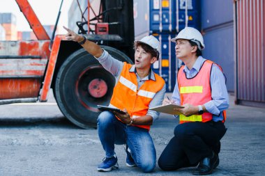 Ekip mühendisi ustabaşı, Asyalı ustabaşı elinde klasör ve tablet kontrol kargo gemisi ithalat, konteyner terminali kargo. Konteyner ithalat şirketinde çalışan memurlar..