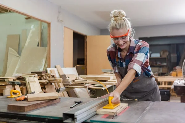 stock image young carpenter woman wear uniform and goggles working use electronic saw cutting wood. craftsman profession in wood factory. woodworking industry.