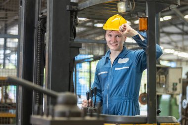 Kafkas mühendis işçilerinin portresi forklift üzerinde duran kameraya bakarken sarı başlık takıyor. Erkek endüstriyel teknisyen gülümsüyor. Basarili isçi makine fabrikası sanayi.