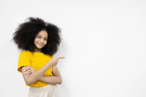 アフロの髪型の肖像幸せな女の子は空のスペースに横にポイント黄色のTシャツを着用します 広告コンセプト 白い背景のメッセージを入力する領域 スペースのコピーテキスト広告の場合 — ストック写真