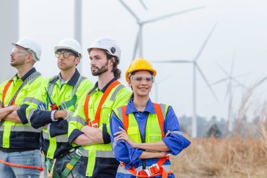 Ekip mühendisinin kadın lideri güvenlik üniforması giyiyor rüzgar türbini alanının yenilenebilir enerjisinde çapraz kollar arasında duruyor. teknoloji çevreyi korur küresel ısınma sorunlarını azaltır.