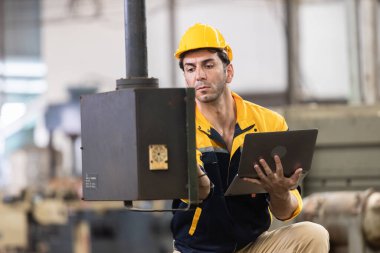 Endüstriyel mühendis üniforma ve kask giyer dizüstü bilgisayar kullanır fabrikada sistem makinesini kontrol ederler. Teknik direktör imalatı. İşçi sanayi fabrikası.