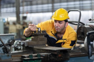 Kafkasyalı mühendis işçiler fabrika endüstrisinde çalışan sarı sapkalı torna makineleri giyerler. Mekanik operatör erkek işçi. Ağır sanayi konsepti.