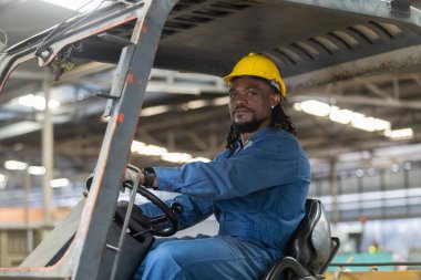 Afrikalı Amerikalı işçi fabrikada güvenlik kaskı sürücü forklift deposu takıyor. Endüstriyel erkek işçi. Konteynır kutusunu kontrol et. Lojistik ihracat konsepti.