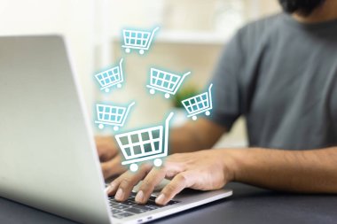 İnternette dizüstü bilgisayar alışverişi yapan bir adam, ekranda alışveriş arabası simgesi. ödemeyi internetten al. Online süpermarket aleti. Müşteri satışı ve ödeme.