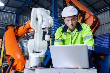 Adam mühendis dizüstü bilgisayar kontrol robot kolu otomatik kullanıyor. Endüstriyel üretim sırasında robot otomasyonu. Fabrikada robotik test performansı.