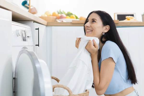 洗濯と家事の概念 休暇で洗濯をする幸せな女性主婦 女性は洗濯機に服を入れている ストック画像
