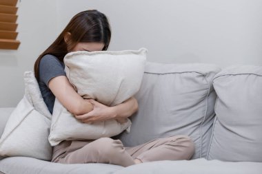 Yatak odasında yalnız başına depresyonda olan bir kadın. Kadın baş ağrısı, mutsuz duygu. Kanepede tek başına oturmak. Depresyondaki kadın yastığı kucaklıyor. Zihinsel sağlık sorunları umutsuzluğa kapıldı.