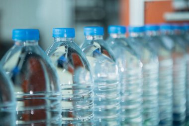 Su içme tesisi. Fabrika üretim hattında seçici odaklı su şişeleri. Suyun plastik şişelere doldurulup tüketicilere sunulması süreci.