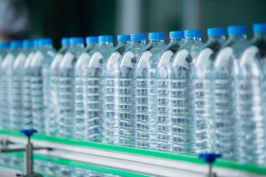 Su içme tesisi. Fabrika üretim hattında seçici odaklı su şişeleri. Suyun plastik şişelere doldurulup tüketicilere sunulması süreci