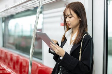 Genç Asyalı kadınlar trenle toplu taşıma ile seyahat ederken tablet kullanıyorlar. Ofis çalışanı sabah işe gidiyor. Demiryolunda güzel bir iş kadını yolcu yolculuğu..