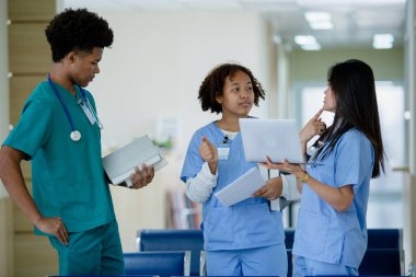 Bir grup tıp öğrencisi hastane üniversitesinde yürürken ve konuşurken üniforma giyer. Eğitim ve öğrenme tıbbi konsepti. Takım çalışması dostu doktor öğrenci..