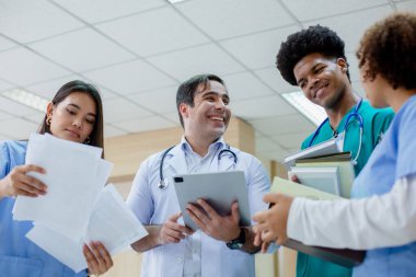 Bir grup tıp öğrencisi elinde öğretmeniyle hastane üniversitesinde sınıfın önünde duruyor. Eğitim ve öğrenme tıbbi konsepti. Sağlık uzmanlarını inceleyin..