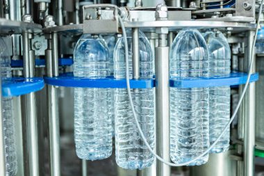 Su içme tesisi. Fabrika üretim hattında seçici odaklı su şişeleri. Suyun plastik şişelere doldurulup tüketicilere sunulması süreci